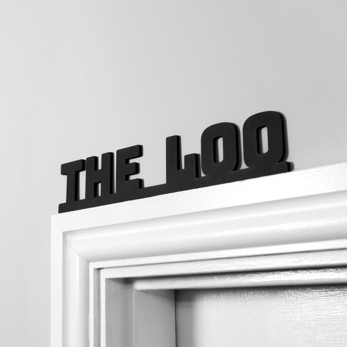 Black The Loo sign mounted on a light door frame