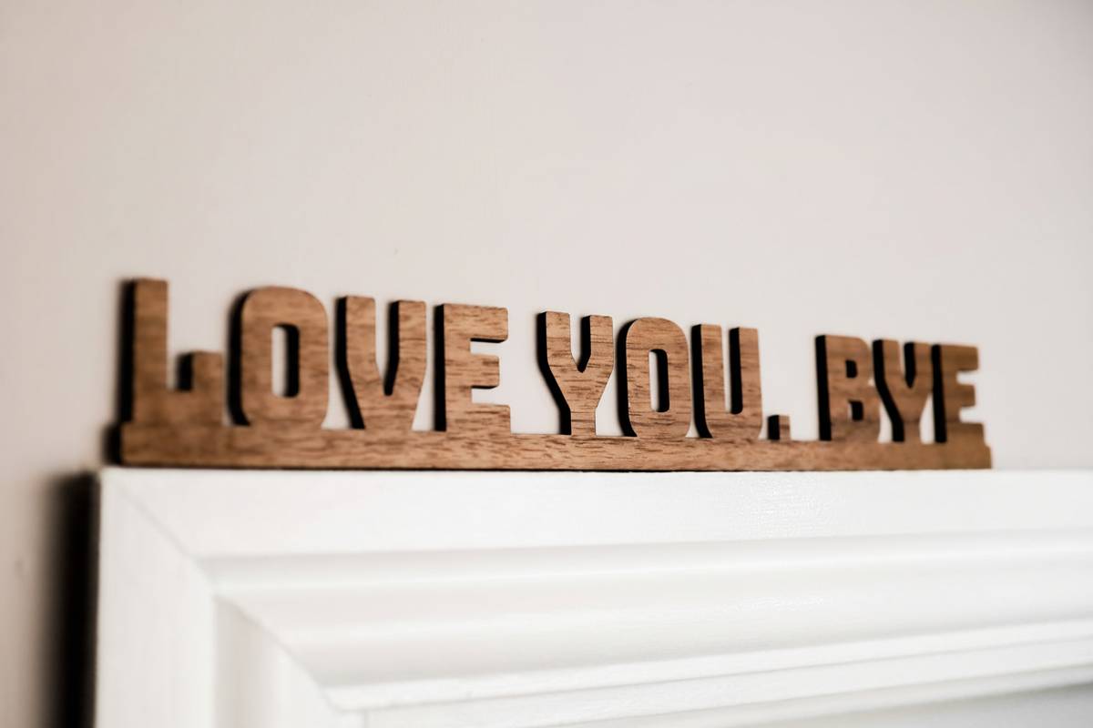 Walnut Love You Bye sign on a light surface