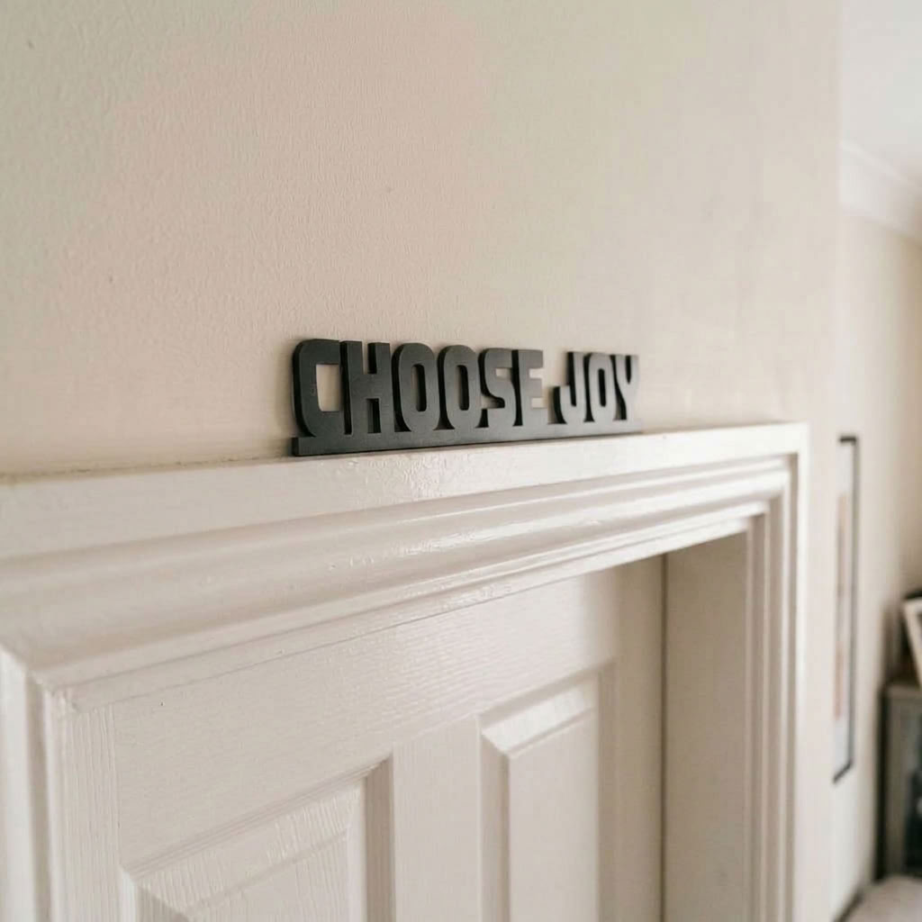 Black acrylic Choose Joy door topper sign above interior doorway