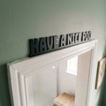 Modern funny bathroom decor sign above white door frame