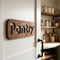 Walnut kitchen pantry sign mounted on a dark pantry door